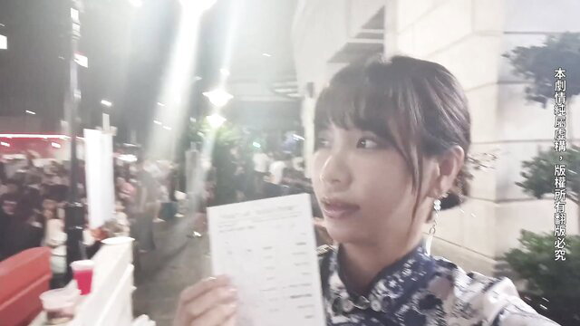 Asian beauty in qipao holds paper at crowded Singapore night event