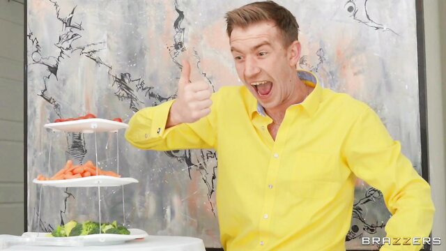 Danny D thumbs up with veggie skewers in yellow shirt Brazzers shoot