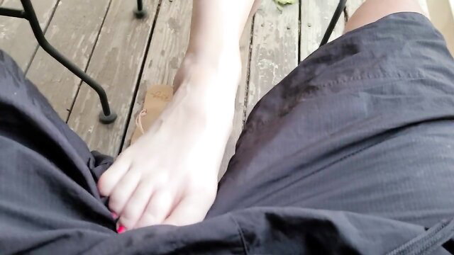 MILF gives outdoor footjob in pants on wooden deck