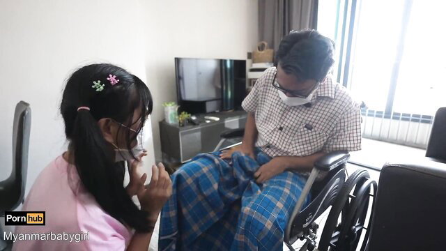 Asian girl in pink touching disabled man's crotch in wheelchair