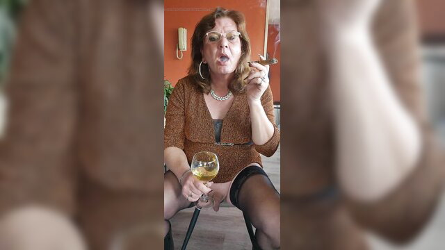 Mature redhead MILF in stockings smokes cigar and sips champagne