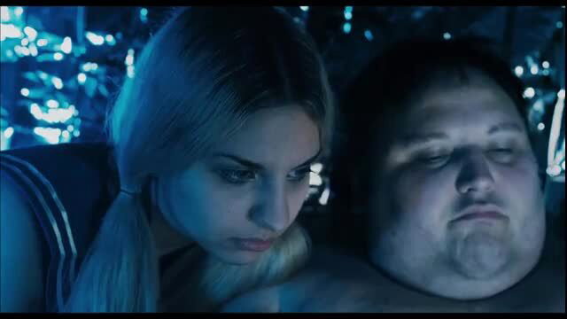 Zehra Zorba topless with chubby man in dark blue-lit scene