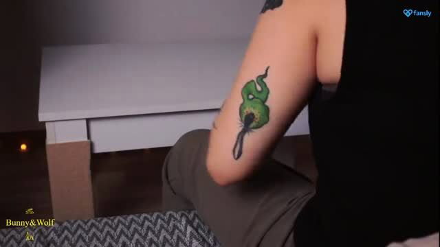 Tattooed Asian babe shows green spider tattoo on arm in dim light