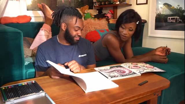 Black dreadlocked guy and ebony woman coloring books on couch, Lior trans top tease