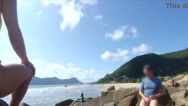 Jane R squats nude by beach rocks, outdoor public tease