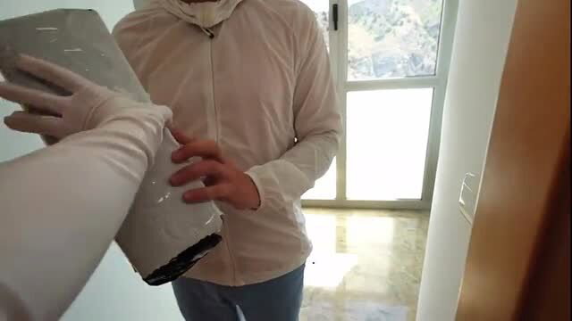 Woman in gloves hands taped package to man at door in teasing tease