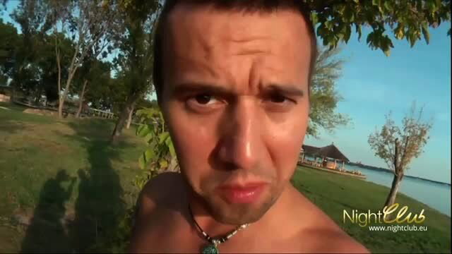 Shirtless man frowning at camera outdoors by the lake