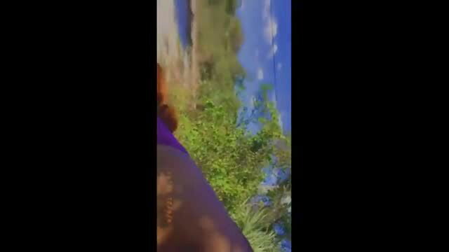Curvy ebony woman in purple bikini by river