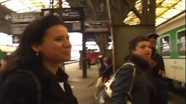 Brunette woman smiling on train platform, outdoor public scene