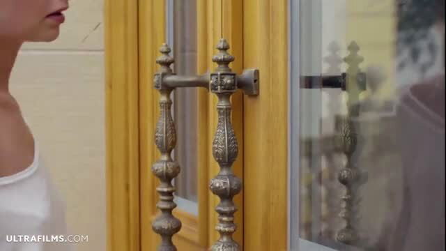 Lady Bug topless in sheer white top by ornate door in outdoor scene