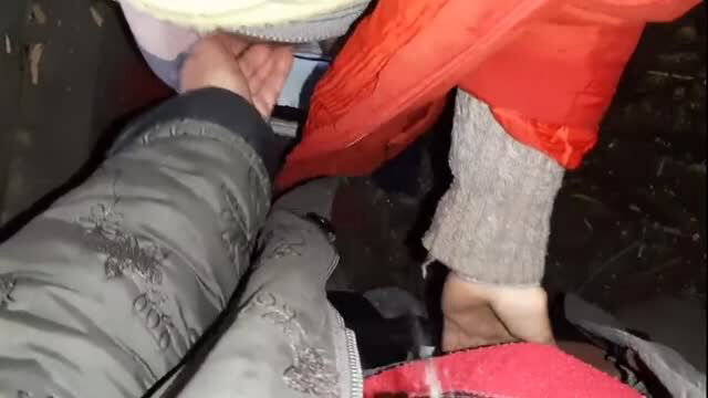 Couple in winter coats intimately touching in dark hut